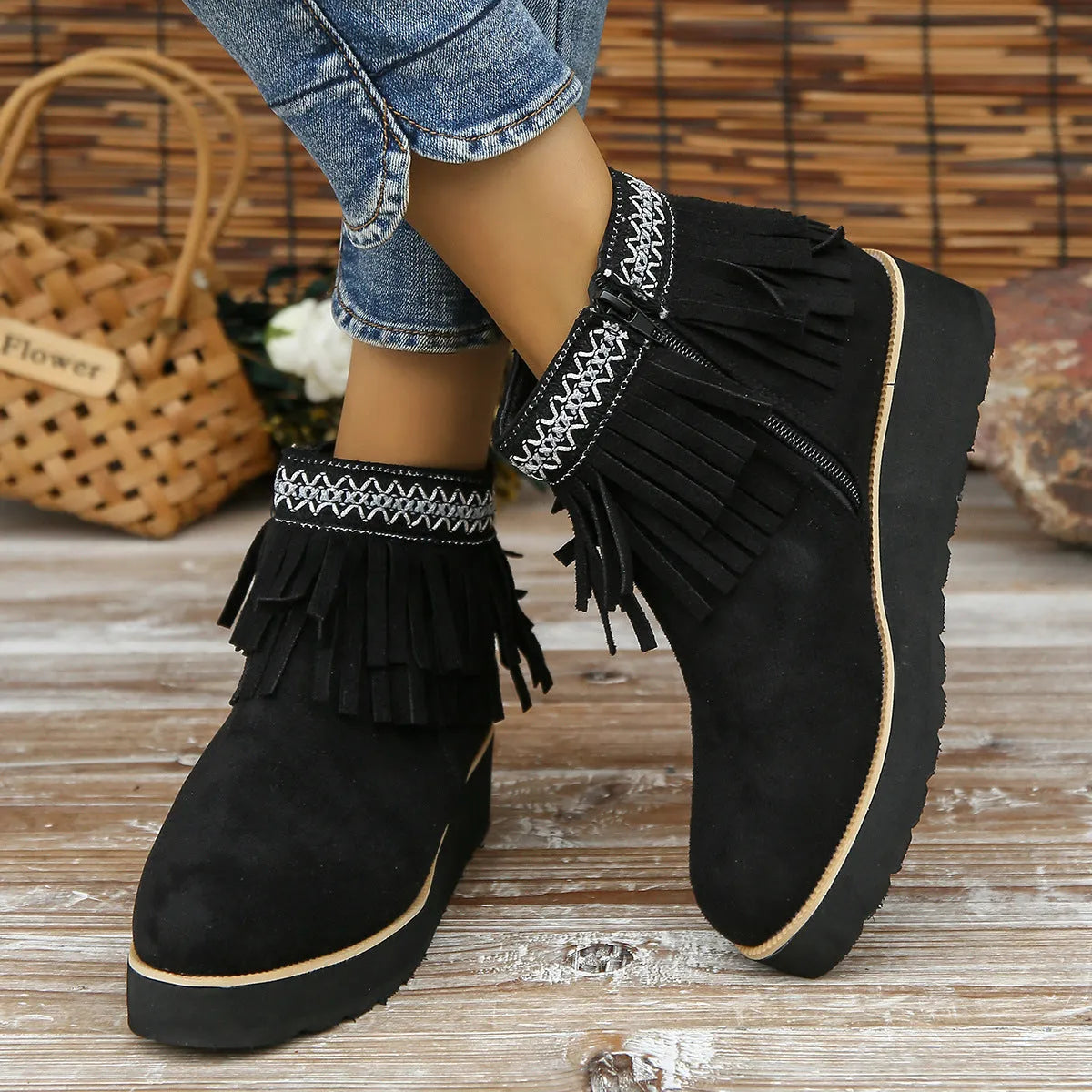 Women's ankle boot in suede with wedge heel, side zipper, and tassel detail on a dark background.