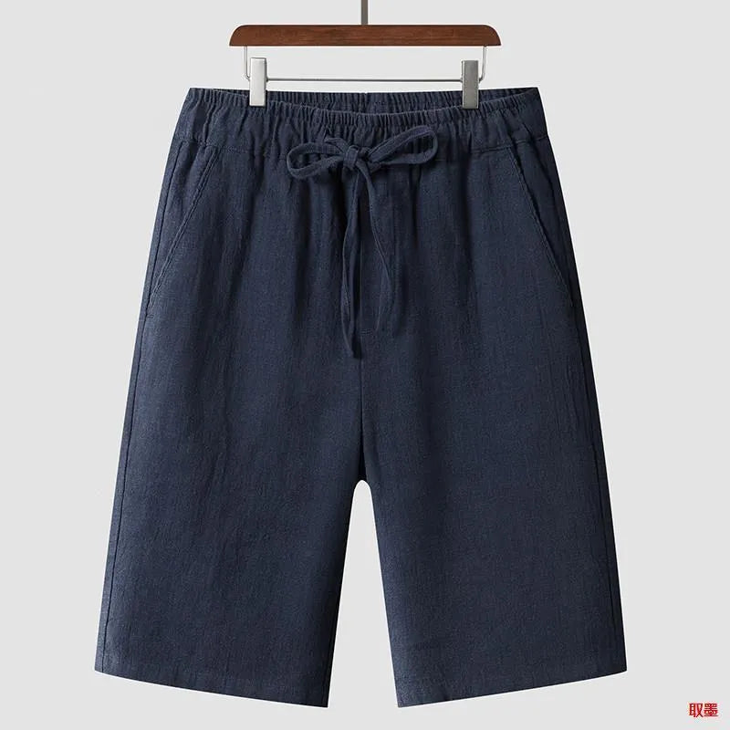 Man wearing beige linen shorts with a loose cropped fit and elasticated mid waist.