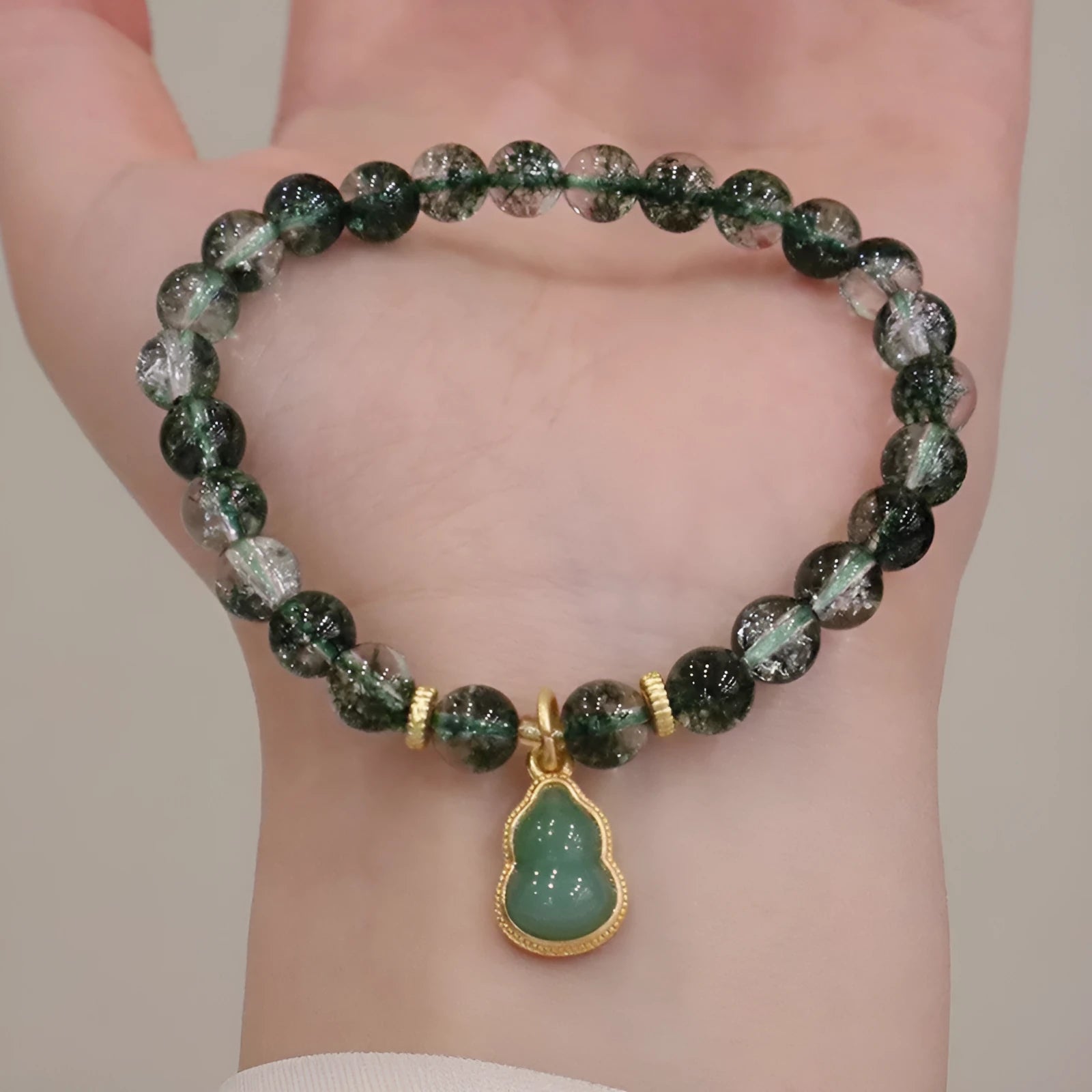 Heart-shaped green phantom quartz crystal bracelet with pearl accents on a neutral background