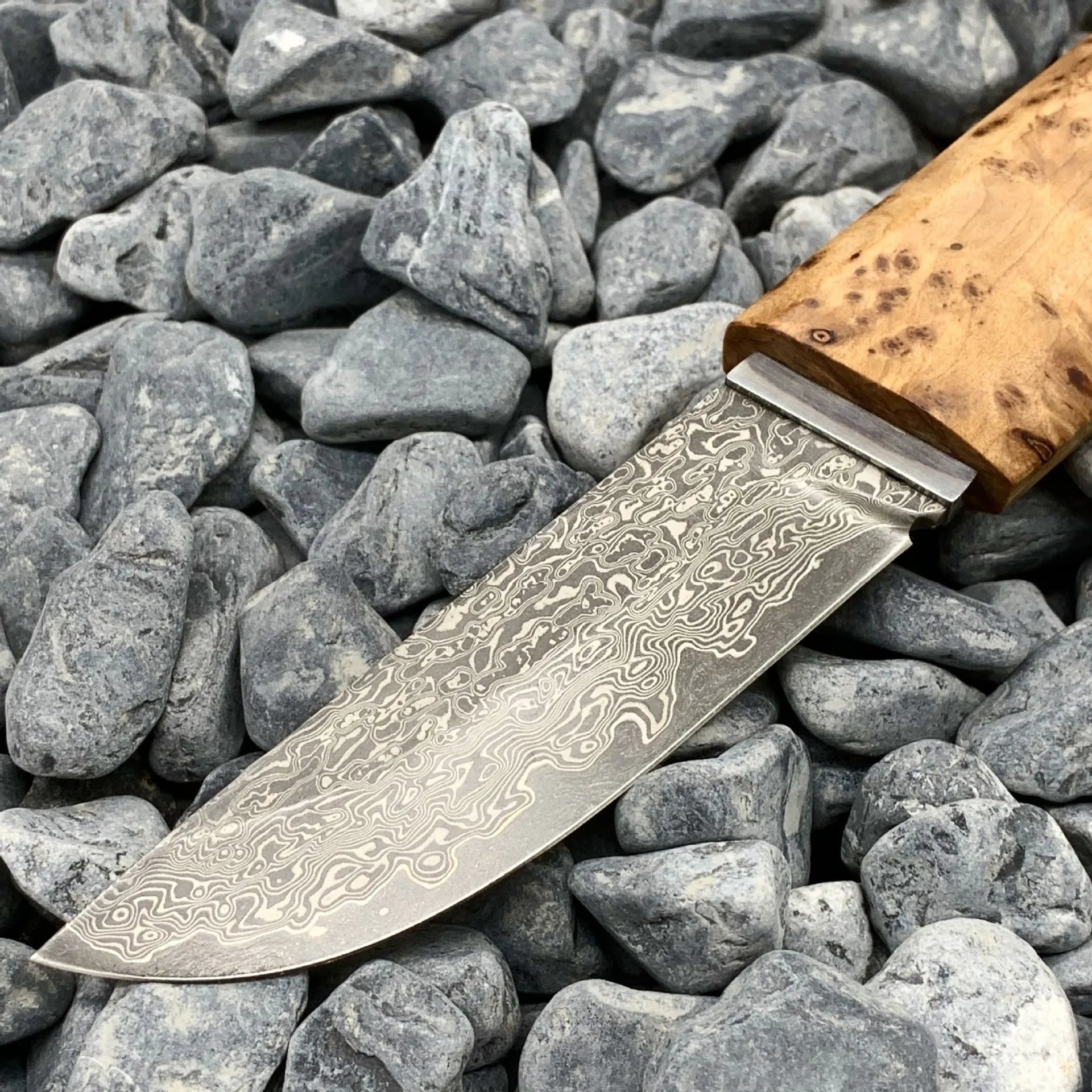 Damascus pattern steel short knife with VG10 steel blade and Thuja wood handle on wooden surface