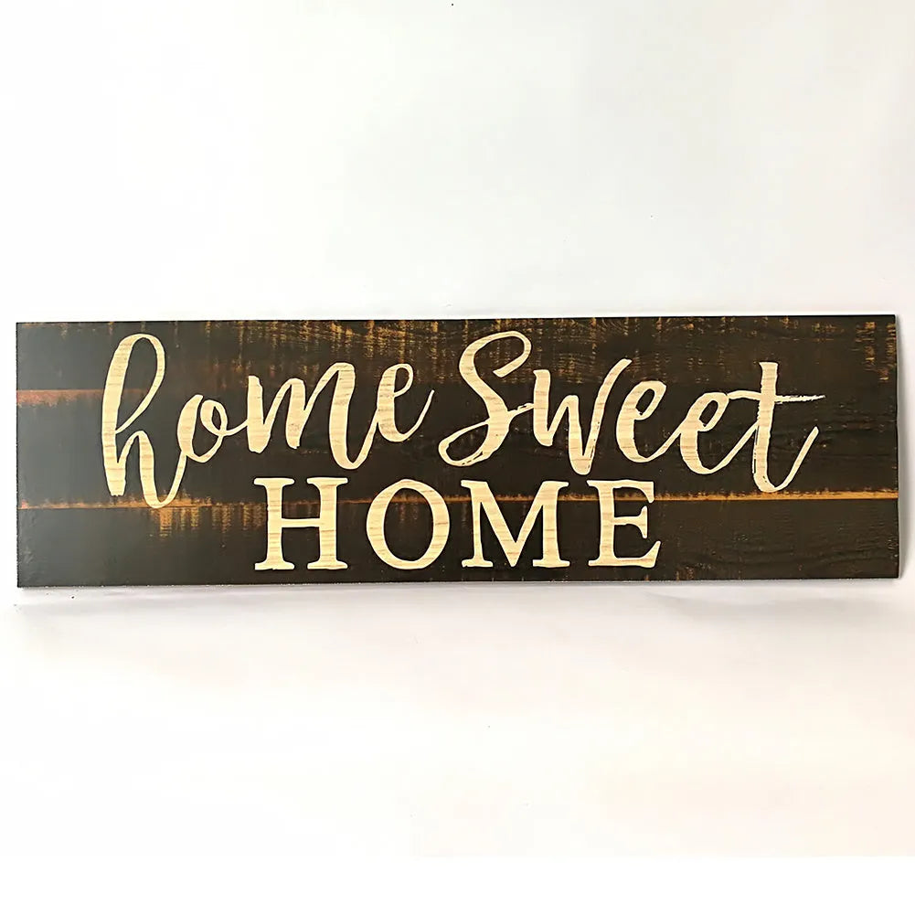 Wooden carved Home Sweet Home hanging pendant decoration in black finish on a light wall