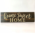 Wooden carved Home Sweet Home hanging pendant decoration in black finish on a light wall