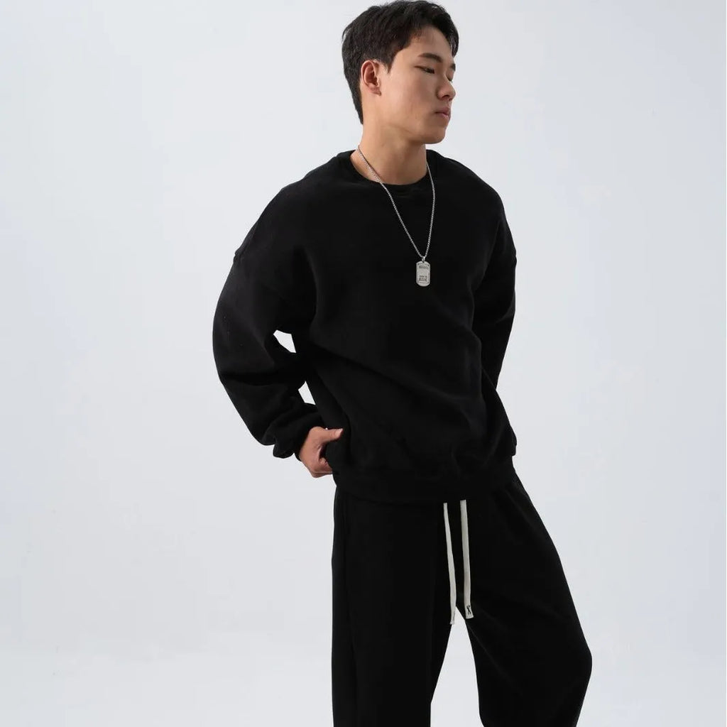 Man wearing a loose-fit black polar fleece jacket and matching trousers, a two-piece winter sports suit.
