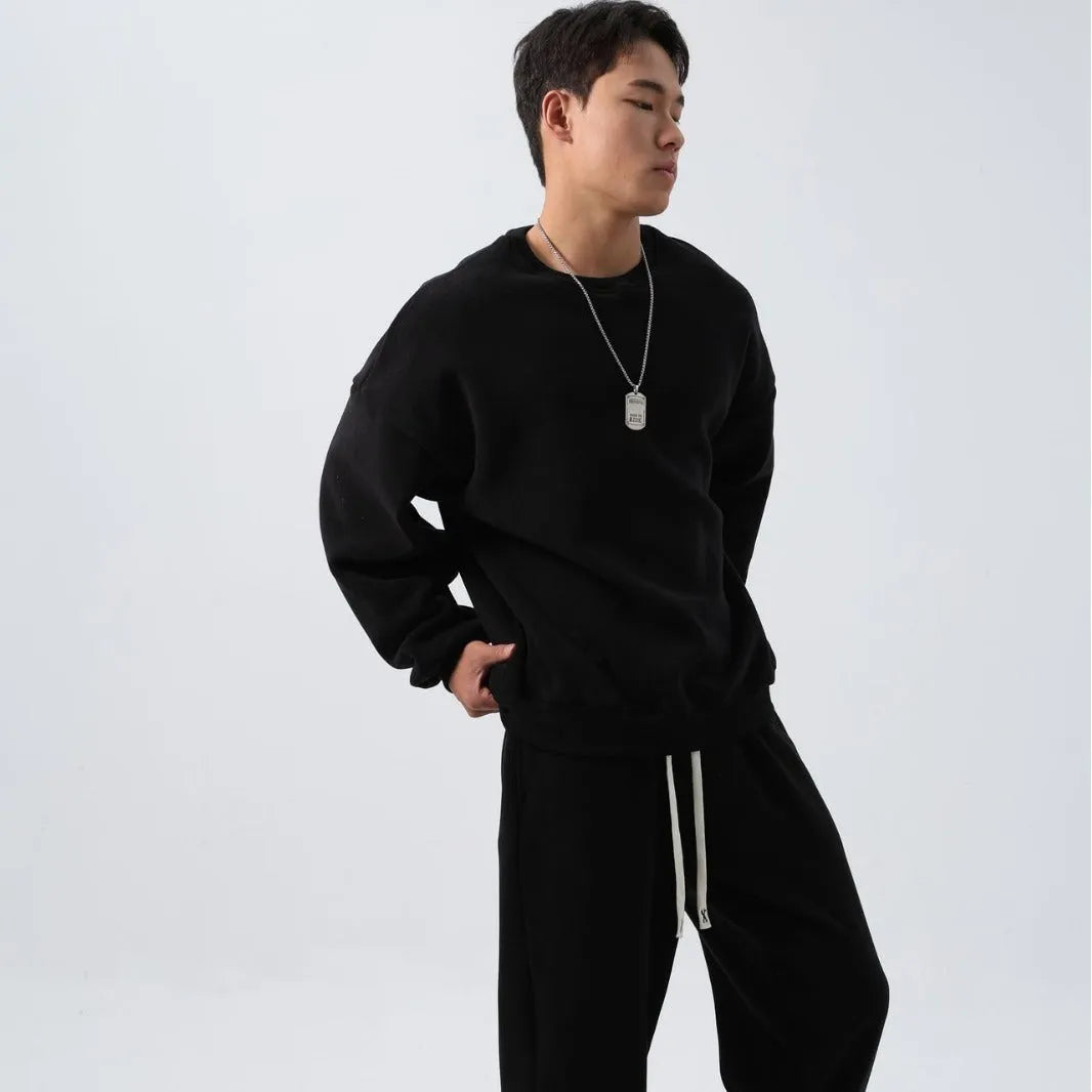 Man wearing a loose-fit black polar fleece jacket and matching trousers, a two-piece winter sports suit.