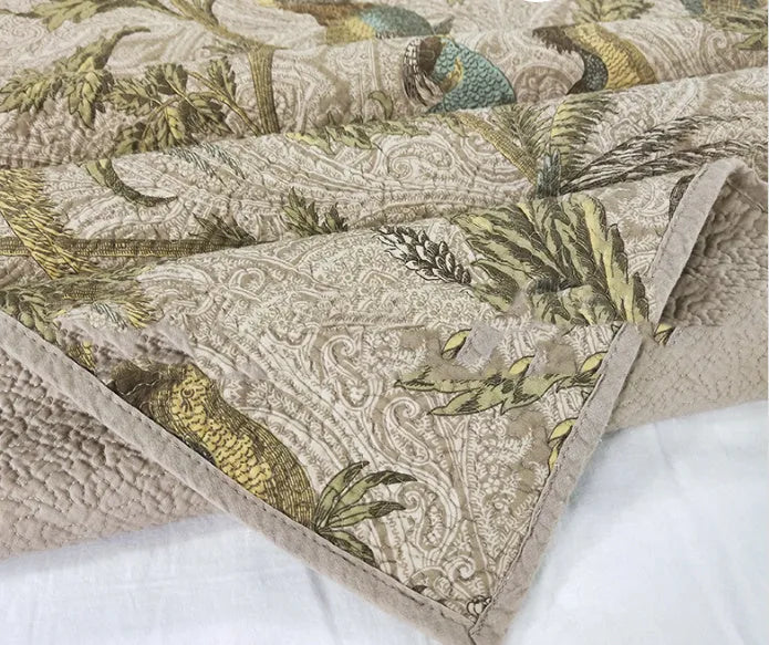 Blue American floral and bird pattern on a pure cotton quilt set with pillowcases, laid on a bed.