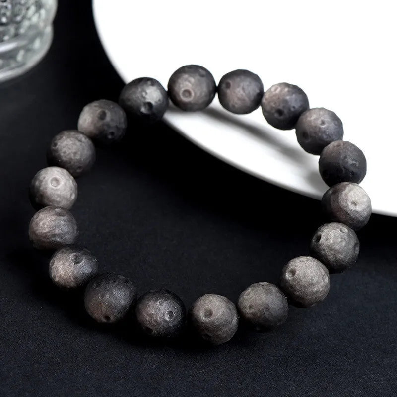 Natural crater ball obsidian bracelet with polished spherical beads showing textured meteorite-style patterns