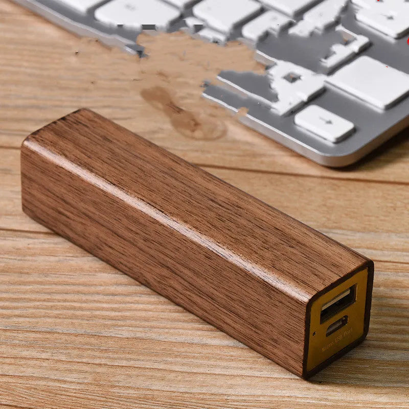 Portable power bank with brown walnut wood shell and USB port on a light background