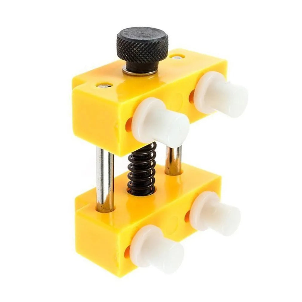 Yellow plastic watch repair case opener kit with mounting base and four fixing pillars on a workbench