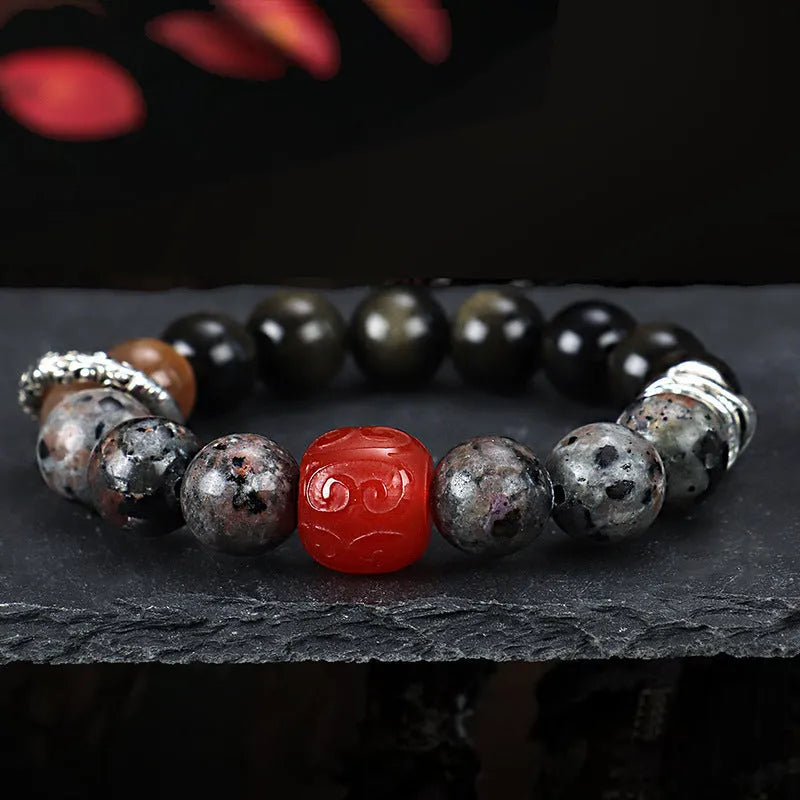 Gold obsidian flame stone and red agate unisex bracelet on a neutral background