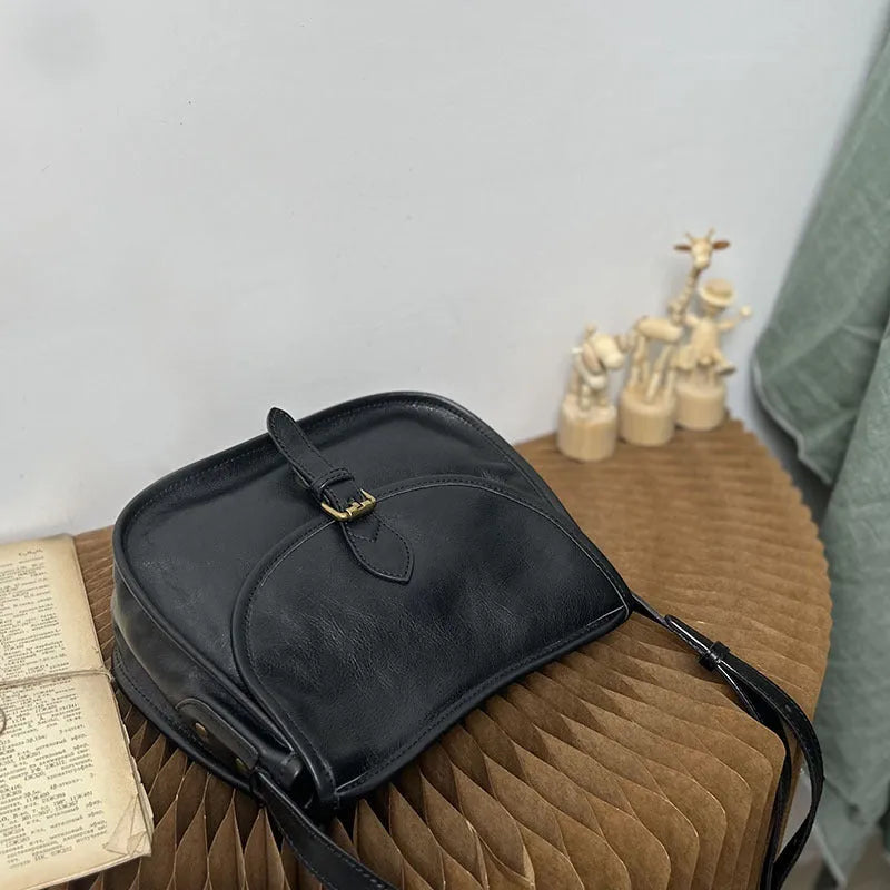 Genuine leather messenger bag in brown, soft shell shape with flap closure and visible sewing detail