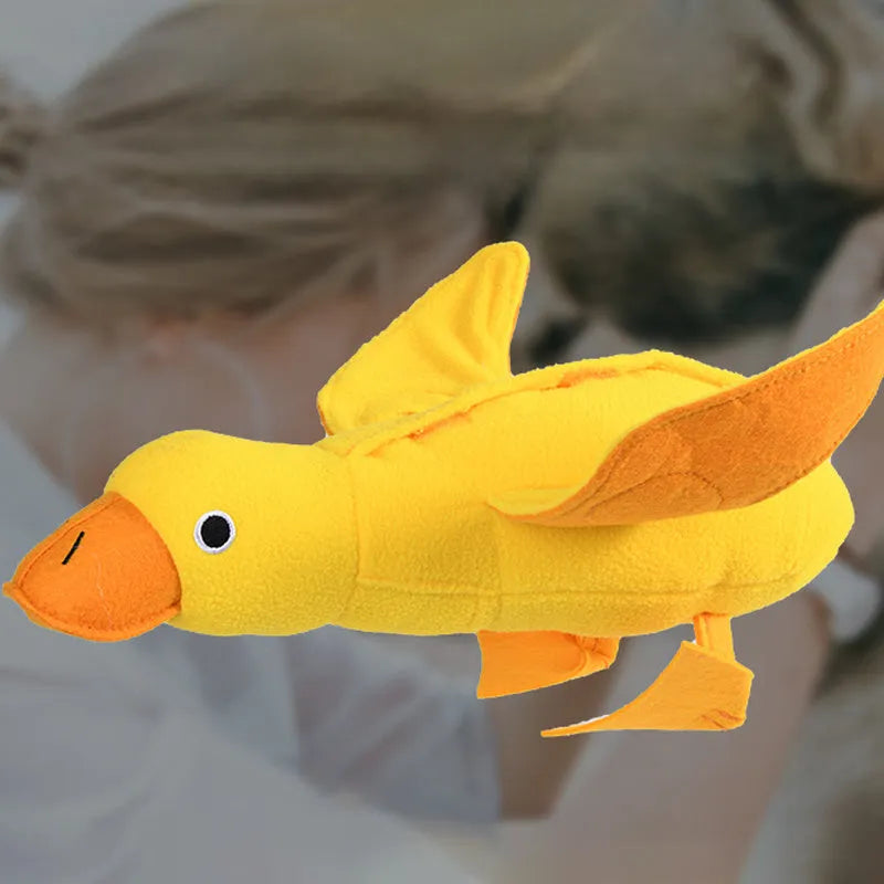 Yellow plush teddy dog toy with a attached duck doll and visible treat pockets on a white background.