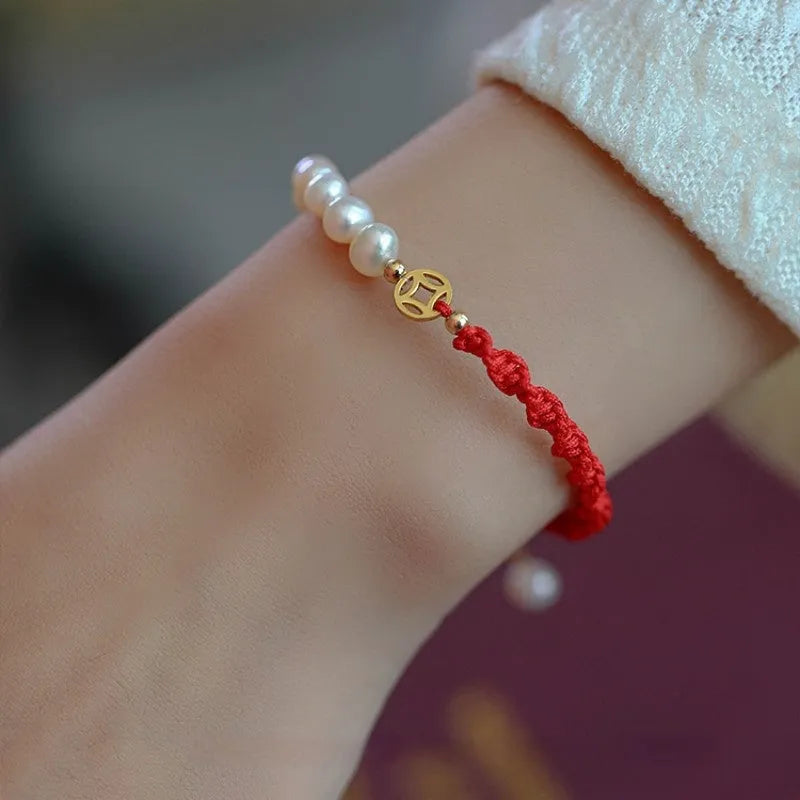 Women's pearl braided red rope bracelet with 14K gold plated fu character charm in geometric shape on white background