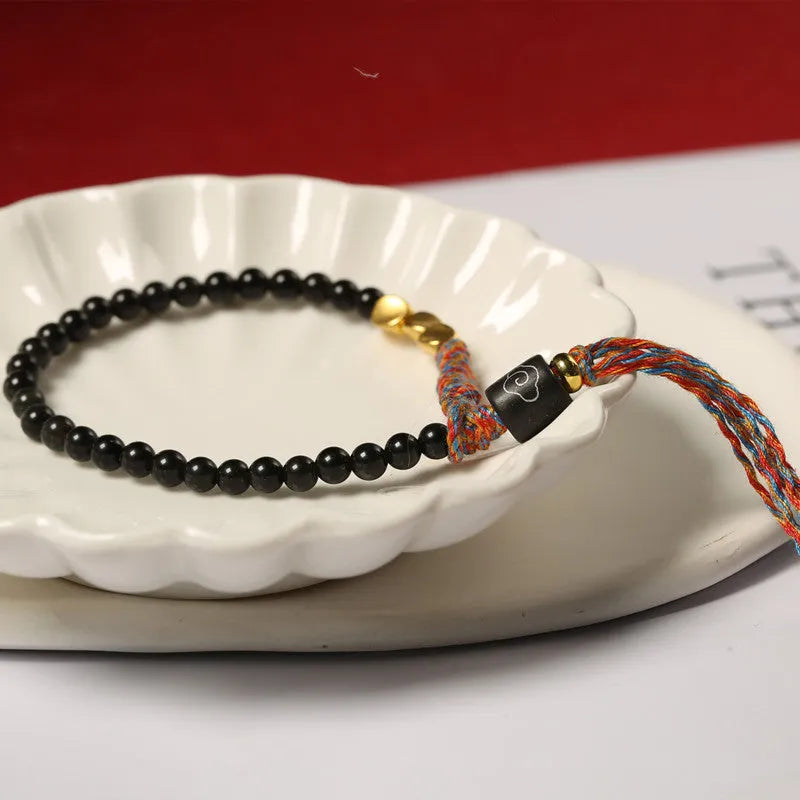 Obsidian coloured hand-woven leather strap bracelet with adjustable fastening on a wrist.