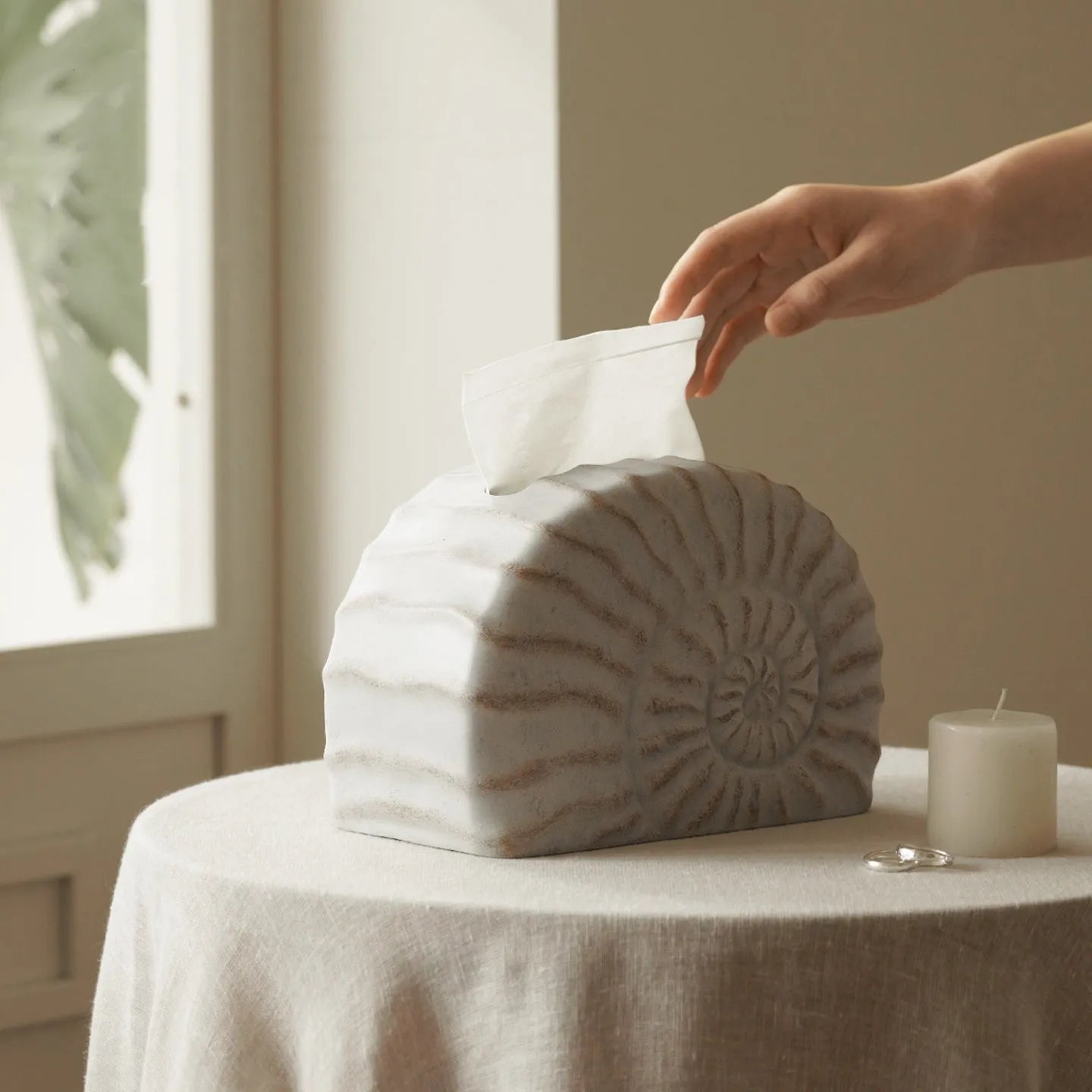 White conch shell shaped resin cover for a rectangular tissue box with a slot for tissue dispensing.