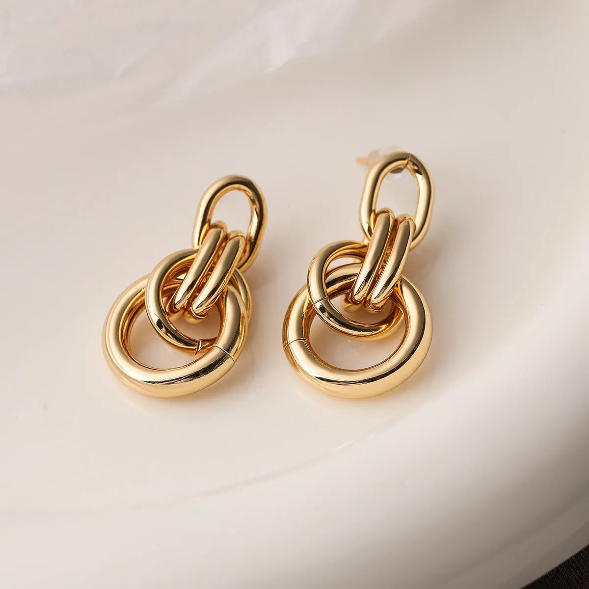 Gold-colour geometric copper earrings for women with an irregular, high-profile silhouette.