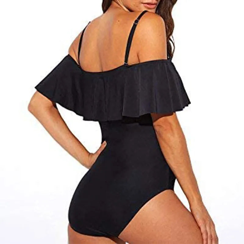 Black one-piece swimsuit with cut-out design and ruffled straps on a tube top.