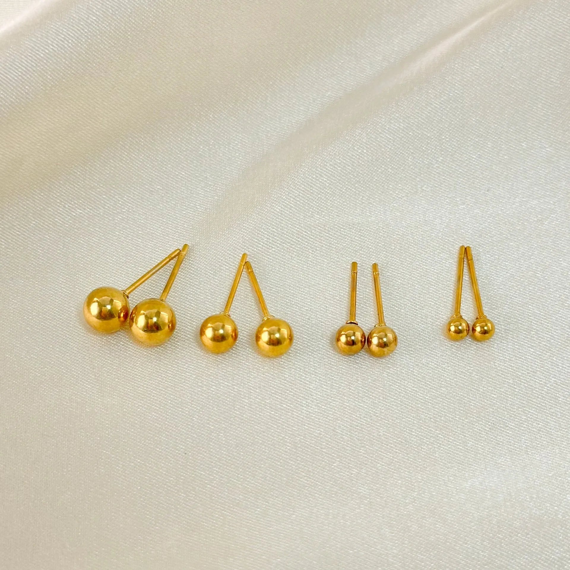 Stainless steel 18K gold ball stud earrings in simple round geometric design on a white background.