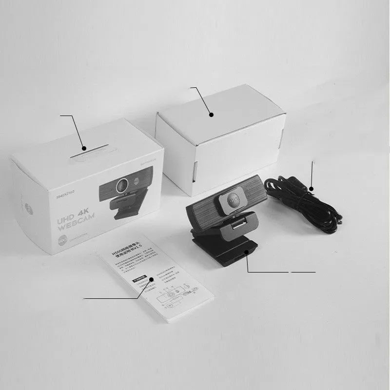 Black USB computer webcam with magnetic privacy cover on a desk next to a laptop.