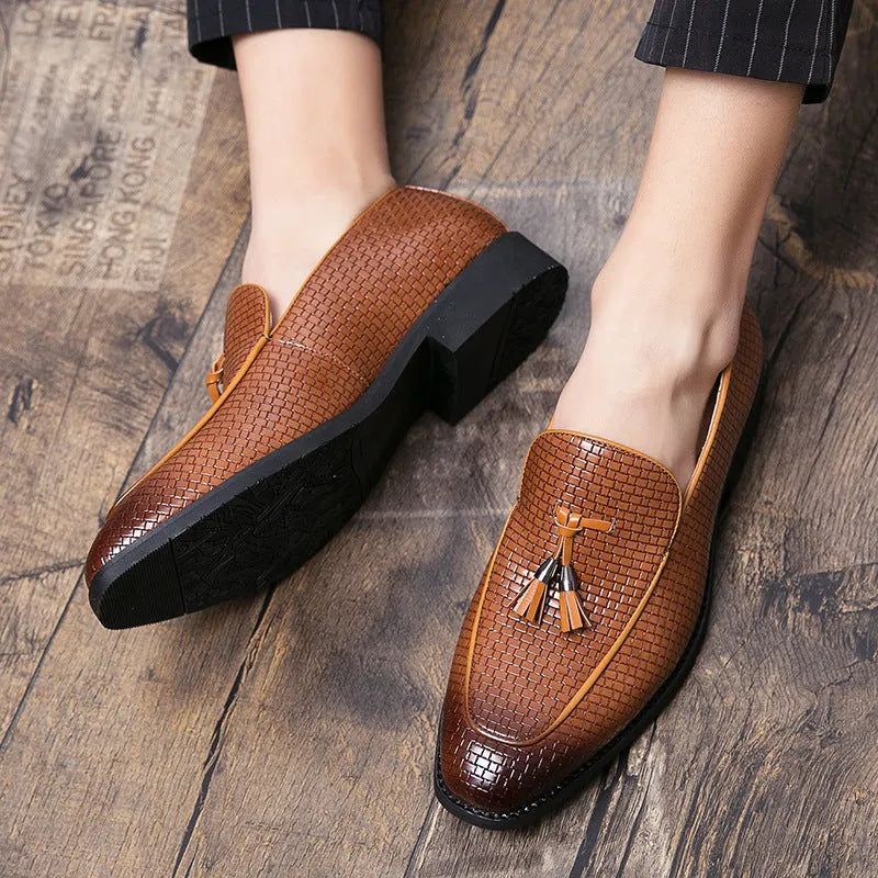 Men's black pointed toe slip-on shoes with a decorative tassel on the front.