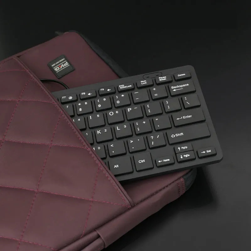 Compact wired USB mini keyboard in black, white, pink, or blue colours on a desk.