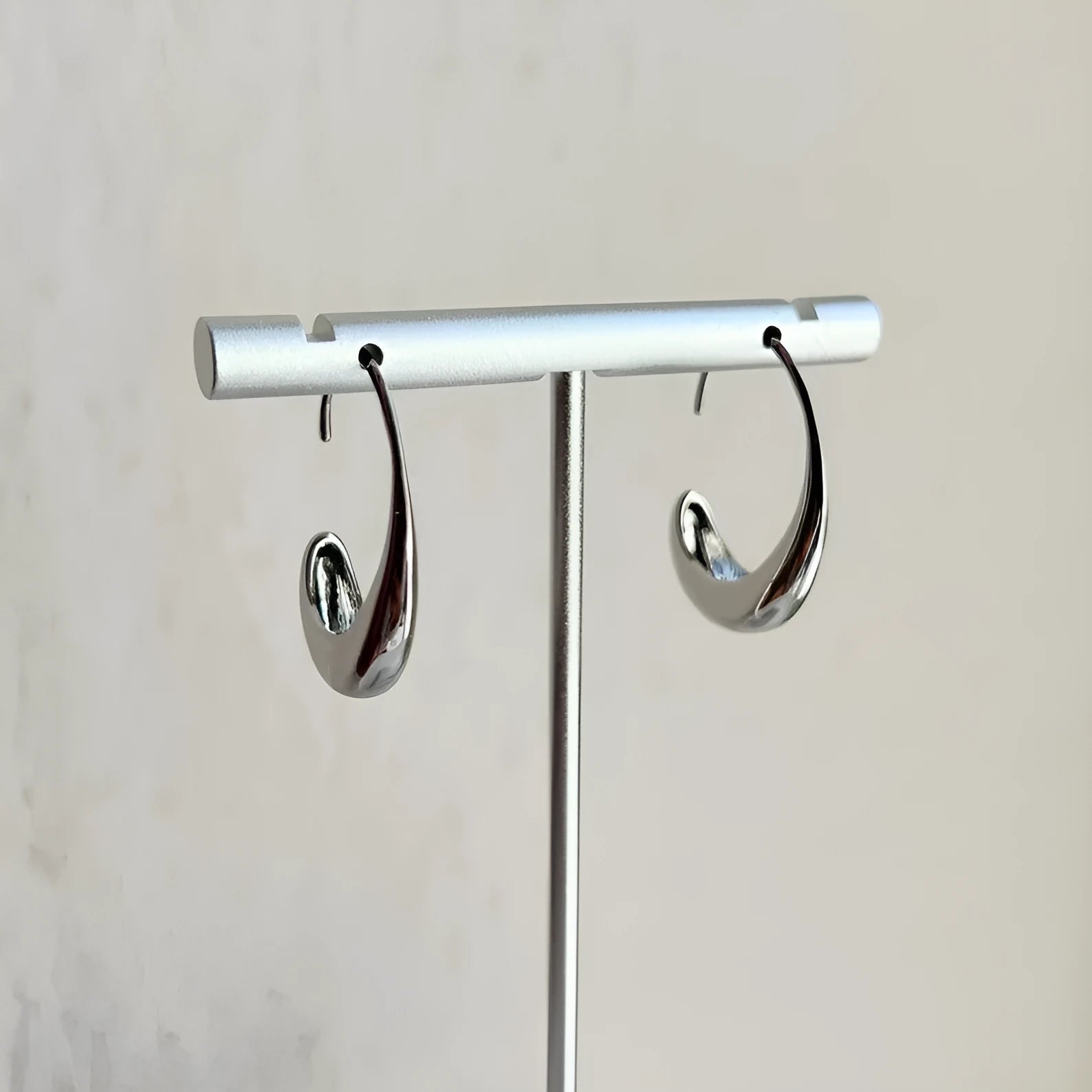 Gold electroplated alloy snake design drop earrings on a neutral background