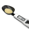 Digital smart measuring spoon with LCD display showing weight reading, on a kitchen countertop
