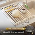 Milky white foldable stainless steel kitchen draining rack placed next to a sink.