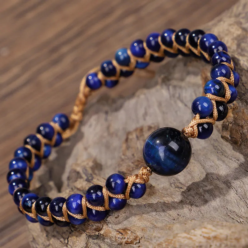 Handmade woven geometric pull bracelet with blue Tigereye stone beads on a wrist.