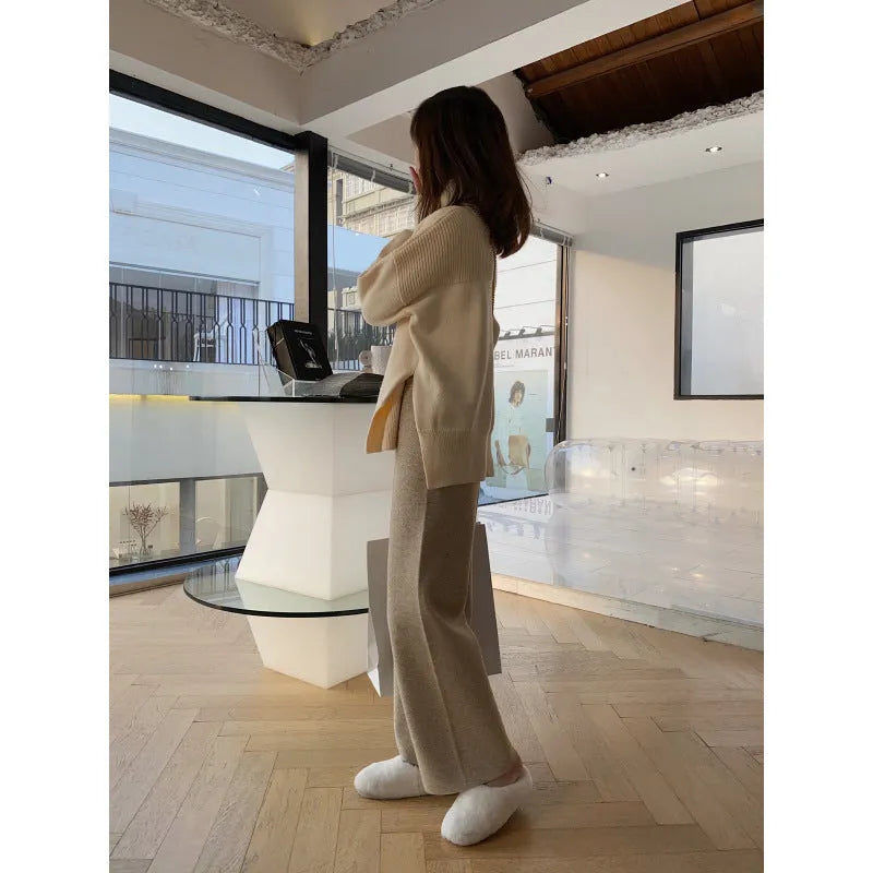 Woman wearing cream white high-waisted knitted wide-leg pants with a drooping mopping silhouette.