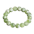Green milk-in-water Xiuyan jade bracelet with polished geometric beads on white background