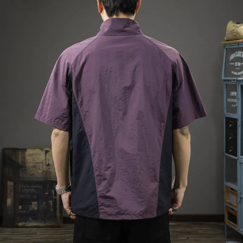 Man wearing a brown short-sleeved shirt with a half-zipped stand collar, showing the loose fit.