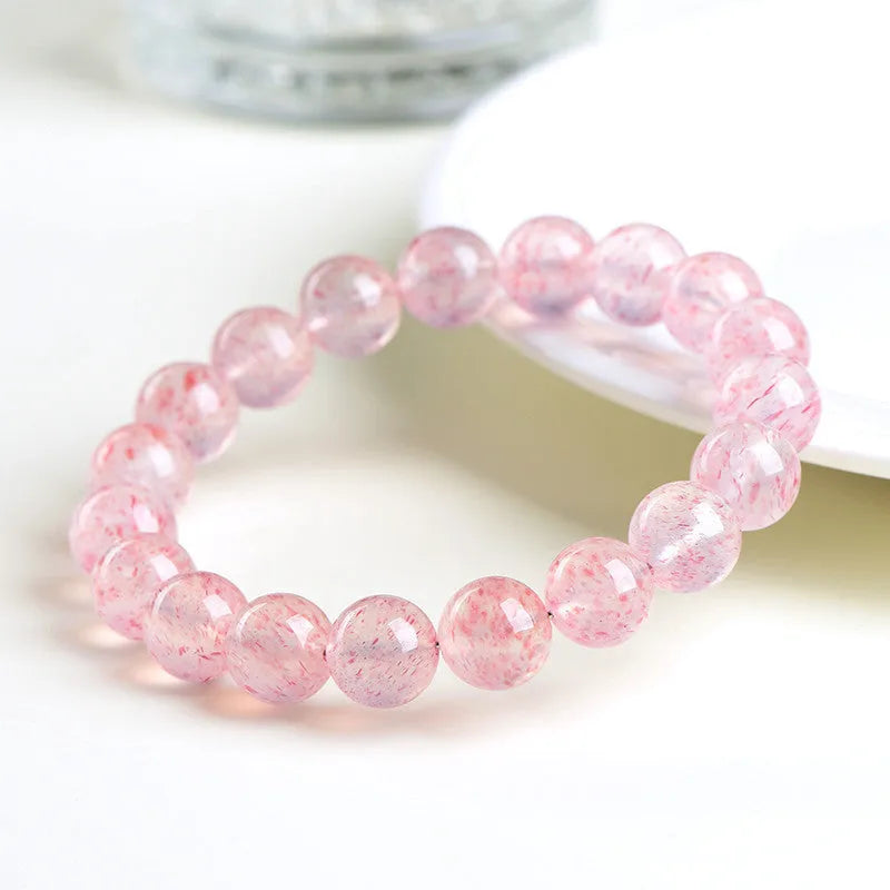 Strawberry quartz crystal bracelet with white geometric beads on a stretch band.