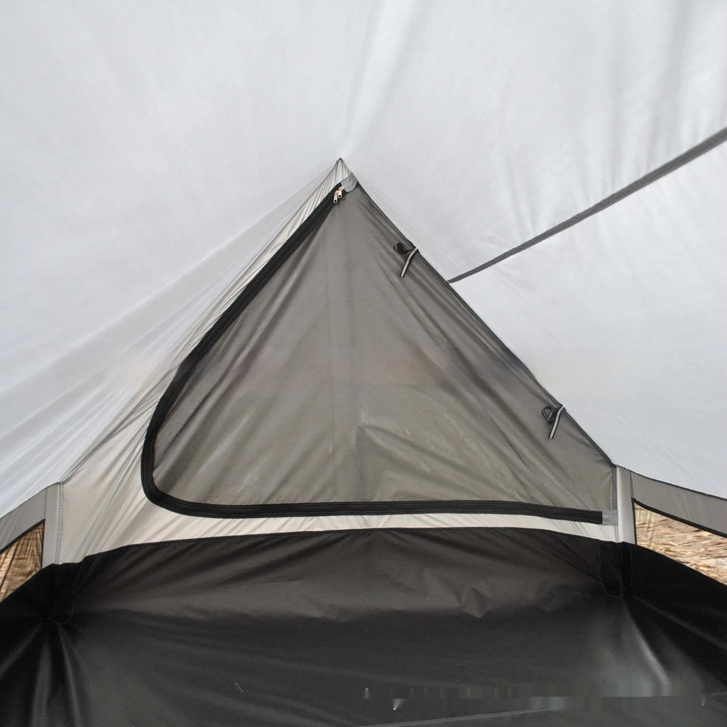 Brown A-line hiking tent set up with trekking poles in a forest clearing.