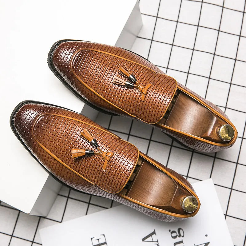 Men's black pointed toe slip-on shoes with a decorative tassel on the front.