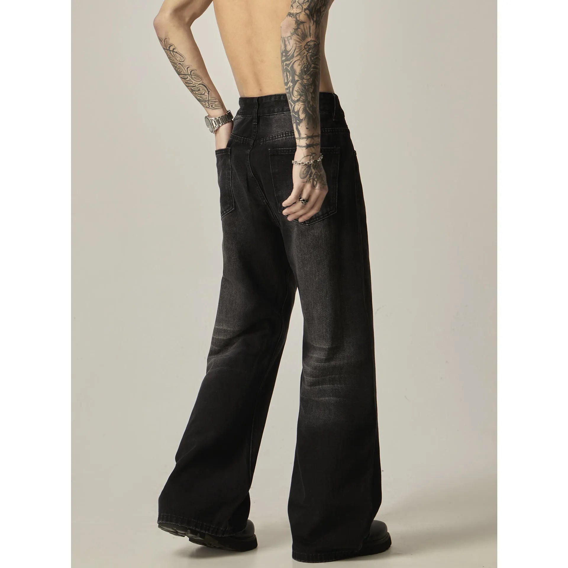 Man's black loose-fit straight-leg jeans with a retro style on a plain background.