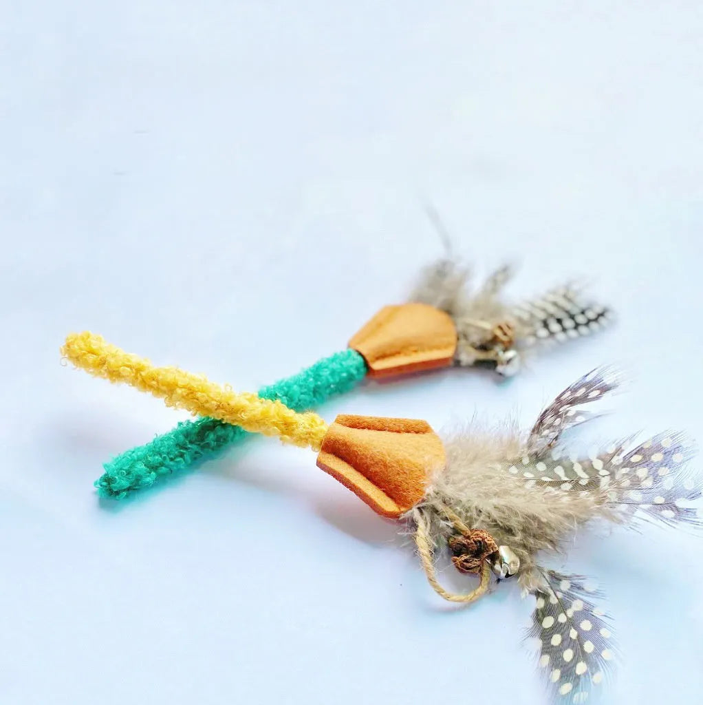 Two polygonum wood cat molar sticks with gall fruit, one green and one yellow, on a neutral background