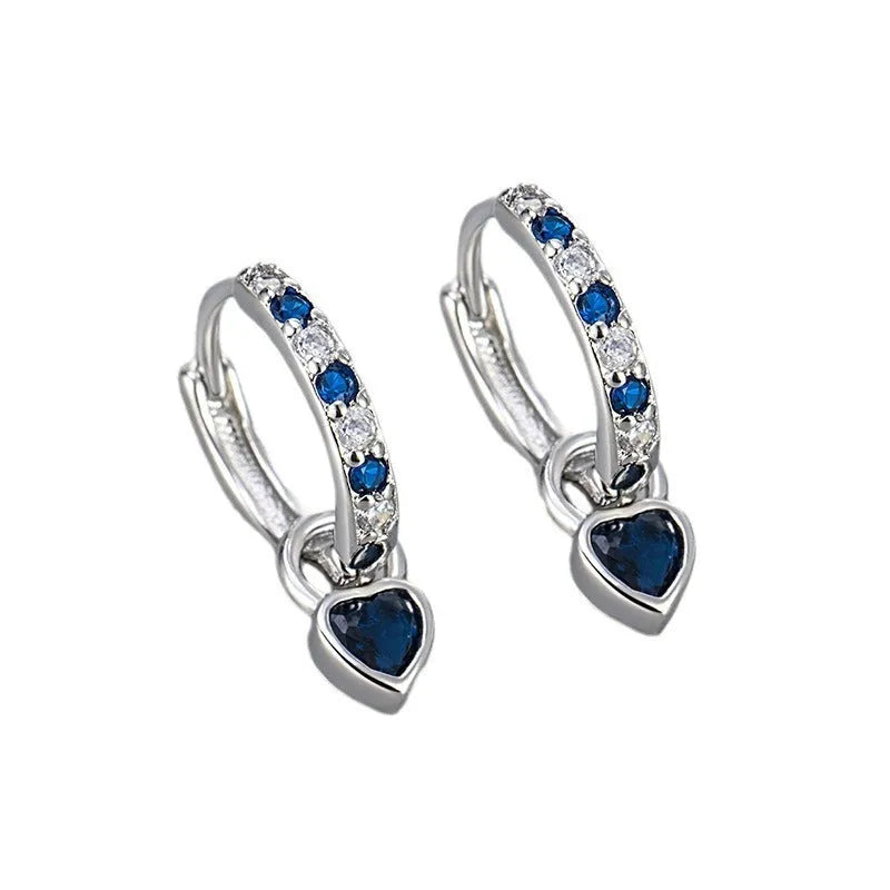 Women's heart-shaped clip-on earring with coloured gemstone centre on a gold-coloured metal setting.