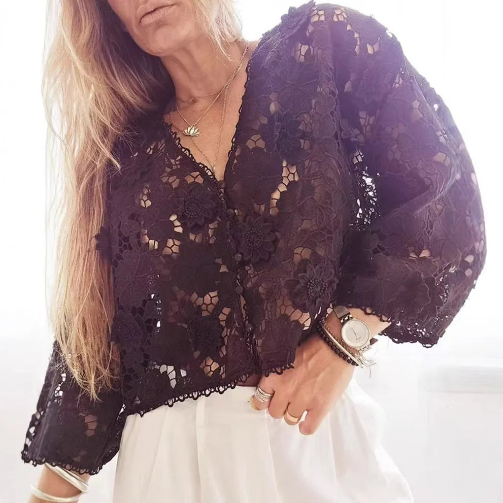 Loose V-neck lace cardigan with white three-dimensional floral decorations on a black background.