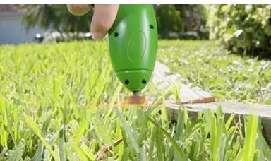 Cordless lawn trimmer with lightweight extension pole and protective debris shield on grass