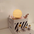 Maglev floating planet night light with three astronaut figures on a desk, showing USB cable and intelligent switch.