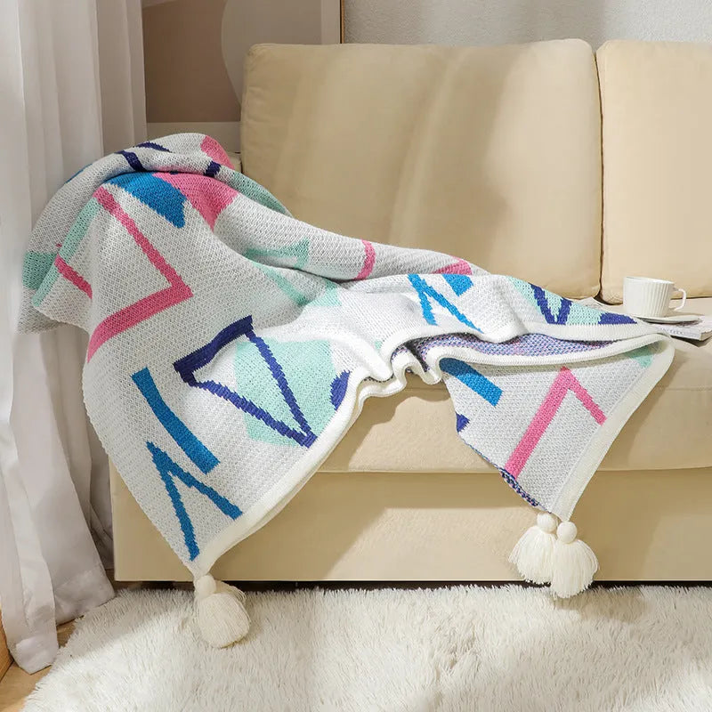 Bohemian style acrylic sofa throw blanket with tassel trim in a geometric pattern colour