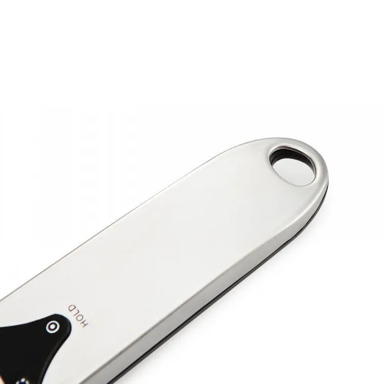 Digital smart measuring spoon with LCD display showing weight reading, on a kitchen countertop