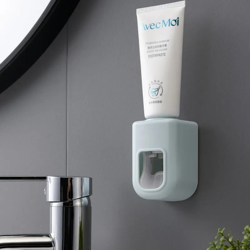 Automatic toothpaste dispenser wall-mounted in blue, with push button and toothpaste nozzle, 9 x 6 x 6 cm