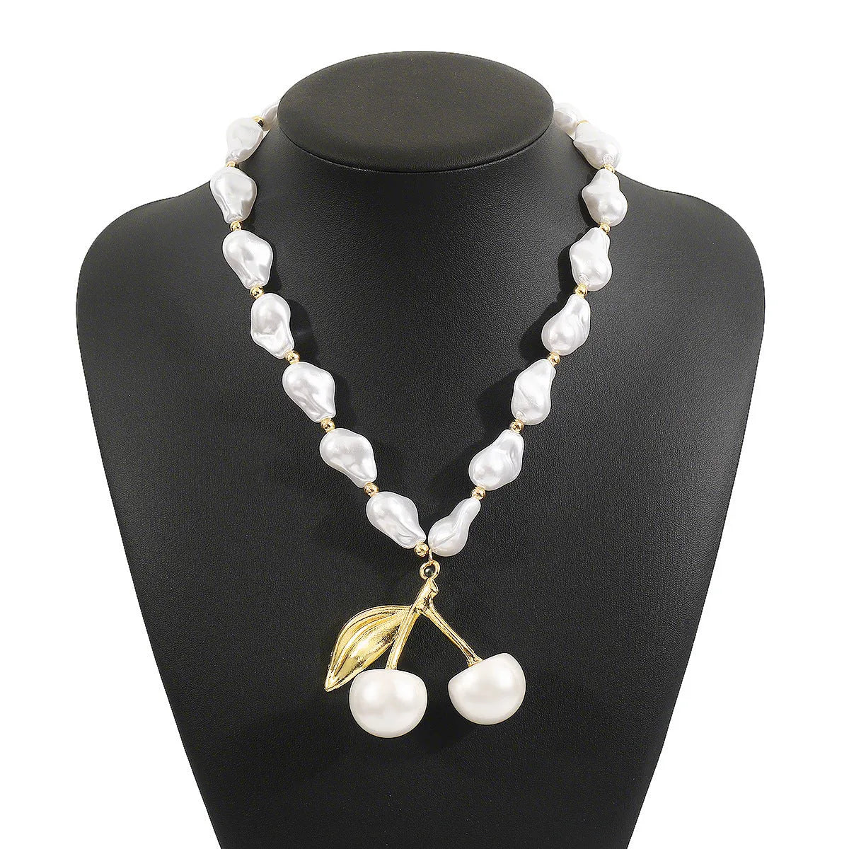 Women's gold alloy necklace with cherry fruit pendant and imitation pearl chain on white background.