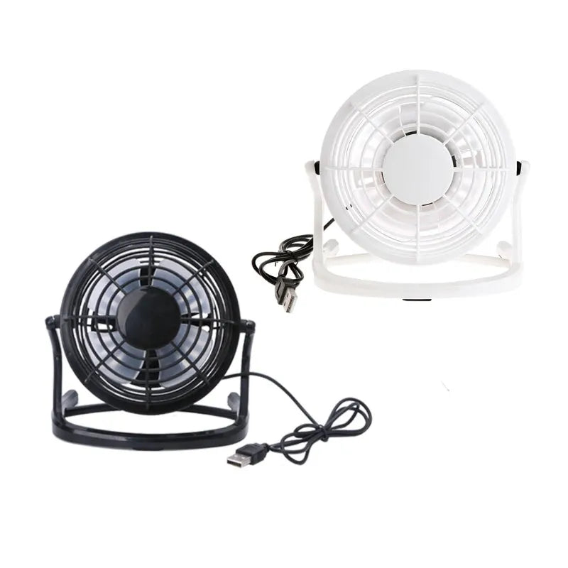 Small black USB desk fan with adjustable head on a wooden desk next to a laptop