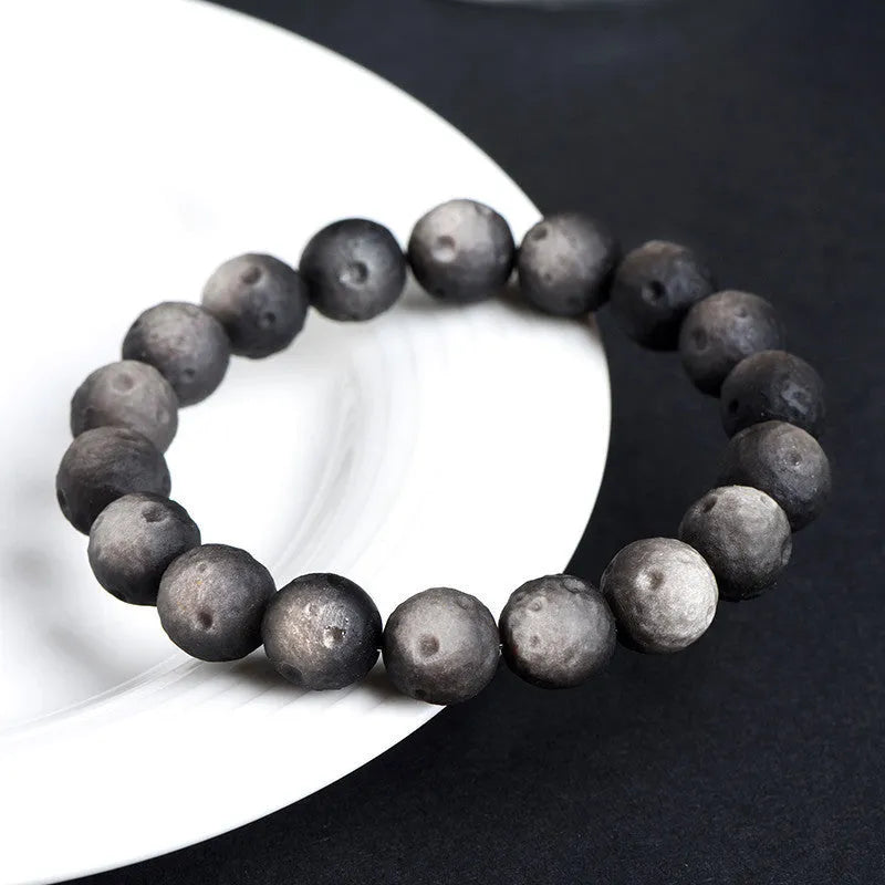 Natural crater ball obsidian bracelet with polished spherical beads showing textured meteorite-style patterns