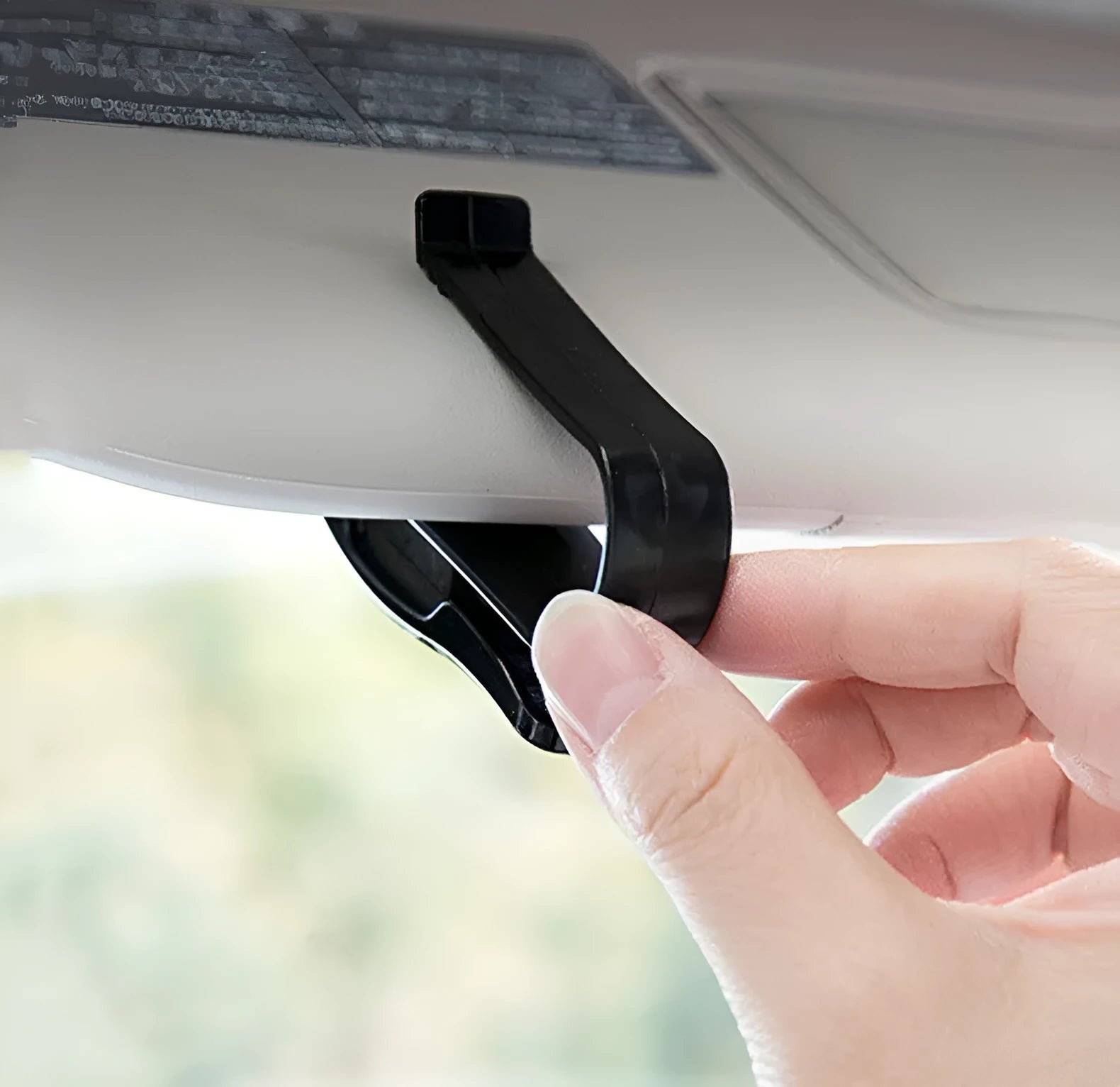 Black plastic clip for car sunshade holding a ticket and glasses