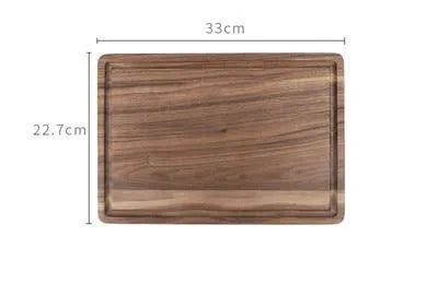 Black walnut wood double-sided cutting board with juice groove and side handle on kitchen counter