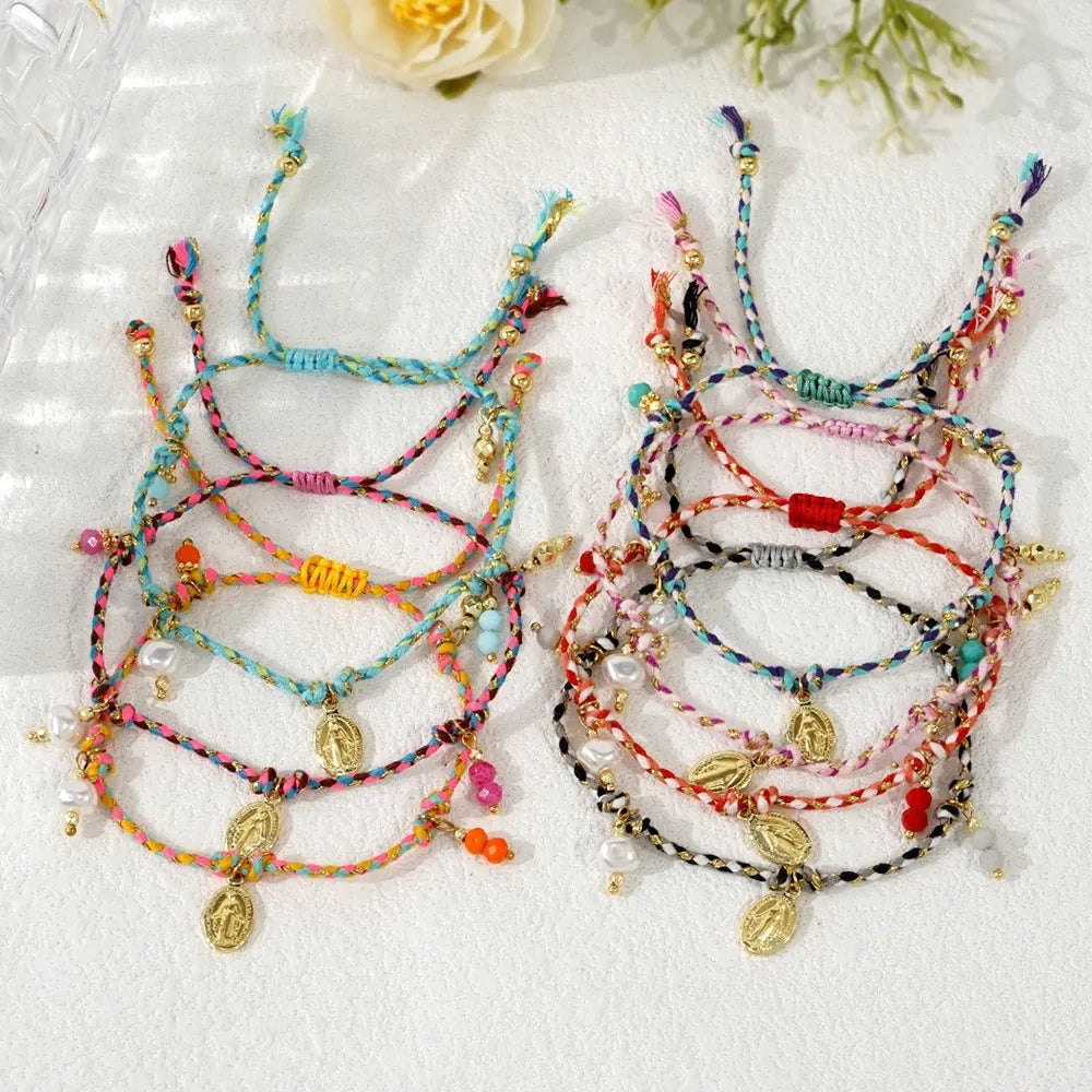 Close-up of a colourful hand-woven braided rope bracelet with a carrying strap tag on a woman's wrist.