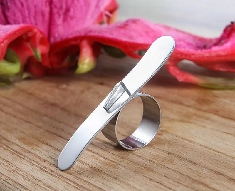 Silver stainless steel ring peeler for citrus fruits on a white background